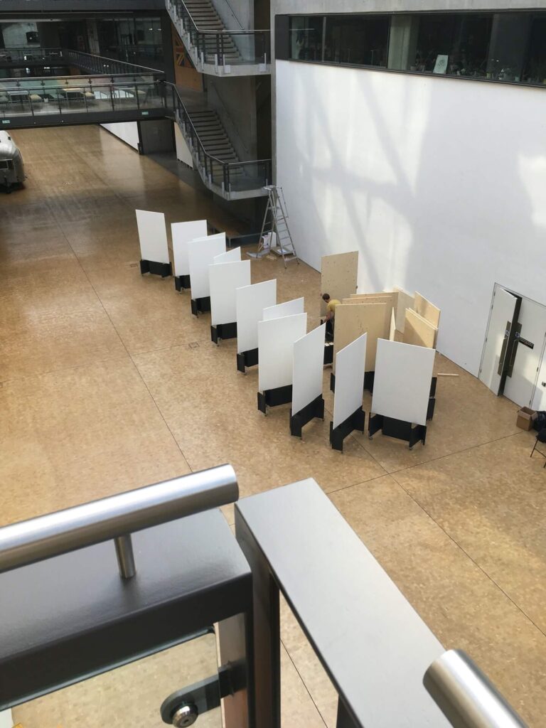 8ft tall display boards being painted white in an art school snake through the hall