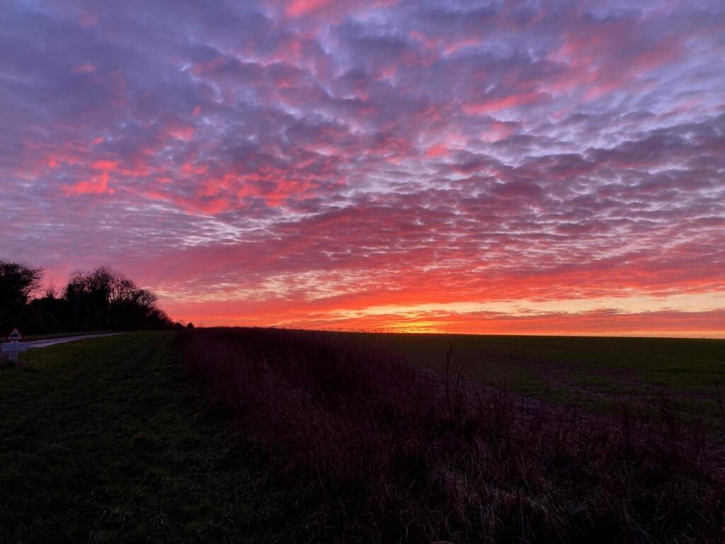 vivid red and orange sunset with a lilac cloudy sky against an horizon in silhouette